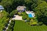 Expansive property featuring a large swimming pool, an outdoor hardscaping area, mature landscaping, a paved circular driveway, and a multi-story exte
