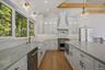 Additional View of Kitchen, cabinetry hood, oversized window with gooseneck lighting