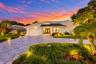 A striking first impression begins with a sweeping paver driveway, lush tropical landscaping, and timeless architectural details that set this home ap