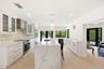 The beautifully renovated chef's kitchen showcases timeless white cabinetry, warm brushed gold accents, Carrara quartz countertops, and premium applia