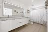 Beautifully updated with a sleek contemporary design, this spacious guest bathroom features an oversized floating vanity with dual sinks, quartz count