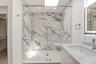 The spa-inspired primary bath showcases a sleek floating dual-sink vanity with quartz countertops, an illuminated designer mirror, and a stunning over