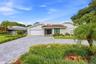 A striking first impression begins with a sweeping paver driveway, lush tropical landscaping, and timeless architectural details that set this home ap