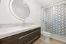 A striking blend of style and sophistication, this beautifully renovated guest bathroom features a custom wood vanity topped with quartz countertops, 