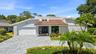 A striking first impression begins with a sweeping paver driveway, lush tropical landscaping, and timeless architectural details that set this home ap