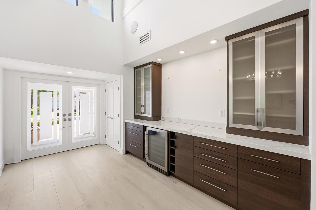Step inside to a stunning foyer where soaring ceilings, abundant natural light, and wide plank white oak porcelain tile flooring create an unforgettab