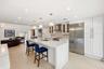 The beautifully renovated chef's kitchen showcases timeless white cabinetry, warm brushed gold accents, Carrara quartz countertops, and premium applia