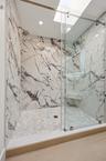 The spa-inspired primary bath showcases a sleek floating dual-sink vanity with quartz countertops, an illuminated designer mirror, and a stunning over