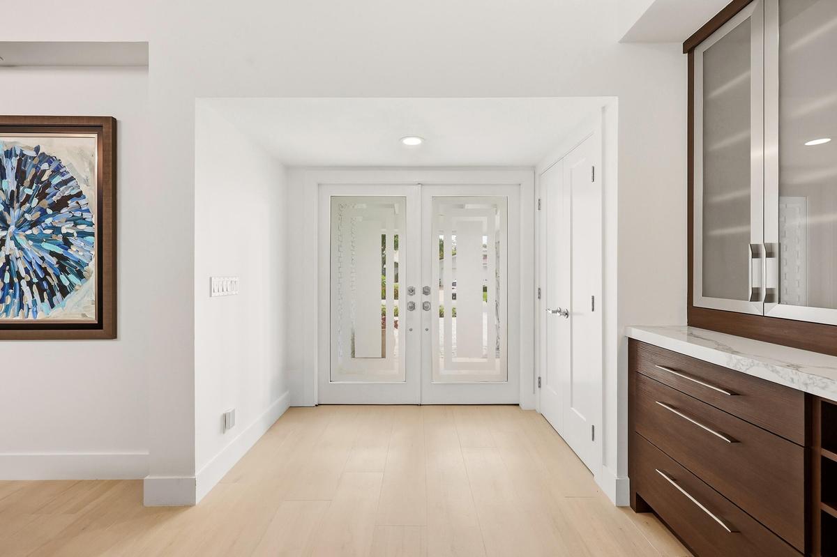 Step inside to a stunning foyer where soaring ceilings, abundant natural light, and wide plank white oak porcelain tile flooring create an unforgettab
