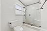 The fully renovated primary bathroom offers dual sinks, updated cabinetry, and a brand-new frameless glass shower.