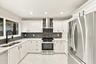 The impeccably upgraded kitchen offers white cabinetry, quartz countertops, stainless steel appliances, and a beautiful charcoal backsplash. There is 