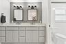 The fully renovated primary bathroom offers dual sinks, updated cabinetry, and a brand-new frameless glass shower.