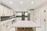The impeccably upgraded kitchen offers white cabinetry, quartz countertops, stainless steel appliances, and a beautiful charcoal backsplash. There is 