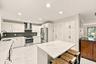 The impeccably upgraded kitchen offers white cabinetry, quartz countertops, stainless steel appliances, and a beautiful charcoal backsplash. There is 