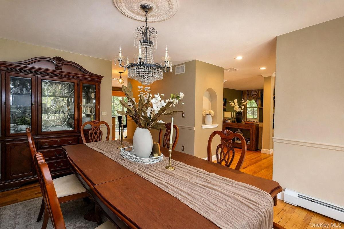 Ornate chandelier with ceiling medallion, hardwood flooring, built-in wall niche, and recessed lighting