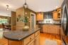 Kitchen featuring wood-finish flooring, light wood cabinetry, dark speckled countertops, center island, stainless steel appliances, and recessed light