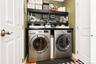 Front-load laundry appliances with a dark countertop and integrated shelving
