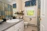 White vanity with under-sink storage, speckled countertop, and a single basin sink