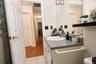 Vanity with integrated sink and speckled countertop, large wall-mounted mirror, overhead lighting fixture and a tub/shower