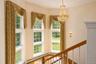 Hardwood flooring with a bay window arrangement, accented by a crystal chandelier and an ornate sconce
