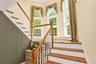 Hardwood staircase with white risers, balusters, landing and wall of windows