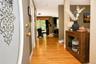Hardwood flooring extends throughout the hallway, complemented by a decorative entrance door and neutral wall tones
