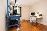 Hardwood flooring throughout, neutral wall paint, and a window with natural light used as an office