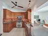 Kitchen featuring wood-finish cabinetry, mosaic tile backsplash, stainless steel range, and an integrated stainless steel sink within a stone countert