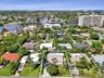 Aerial perspective featuring a residential street, a maturely landscaped property, and swimming pool