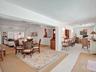 Open concept living area featuring white walls, vaulted ceilings, and a combination of light wood-finish flooring and neutral carpeting