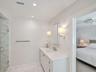 Bathroom featuring a white vanity with an undermount sink, a stone-finish countertop, and wall-mounted sconce lighting