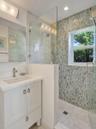 Glass-enclosed shower with mosaic wall tile.