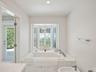 Recessed lighting, bay window with plantation shutters, built-in soaking tub with marble surround, polished chrome fixtures, and bidet