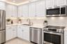 White shaker-style cabinetry, stainless steel appliances, light-toned countertops, undermount sink, and recessed lighting