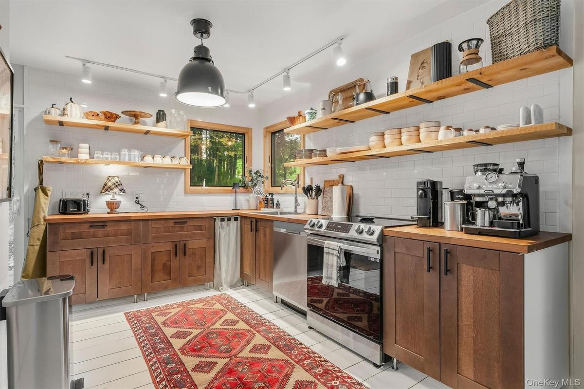 Modern country kitchen with stainless appliances, open shelving, herringbone wood counters