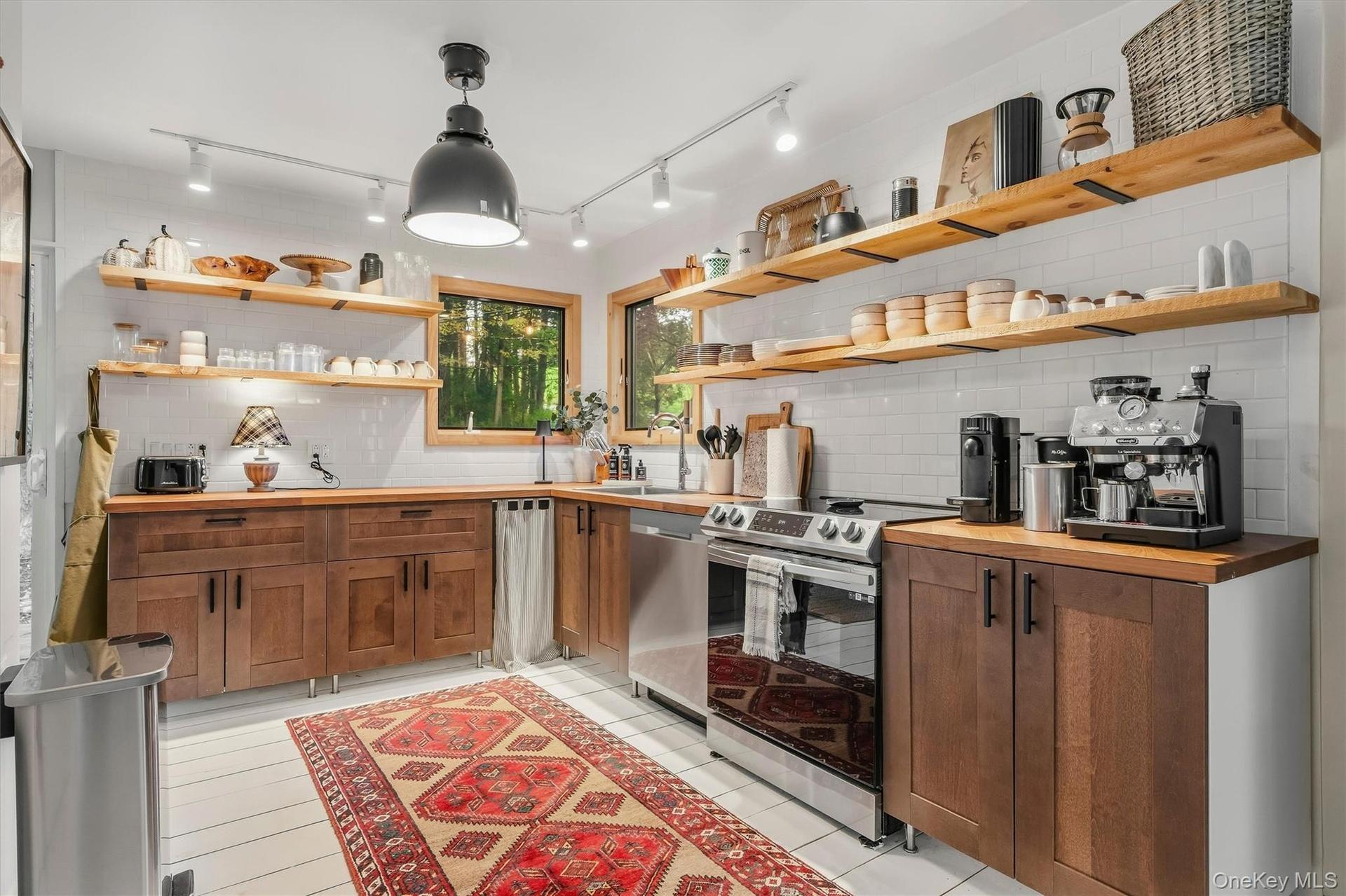 Modern country kitchen with stainless appliances, open shelving, herringbone wood counters