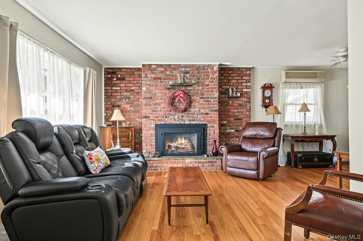 Spacious living room with hardwood floors and a charming brick gas fireplace.