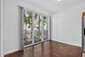 Wood-finish flooring with floor-to-ceiling sliding glass doors opening to a balcony with metal railings