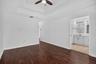 Wood-finish flooring, tray ceiling, ceiling fan, and an en-suite bathroom featuring a double vanity with an integrated mirror