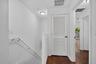 Hallway featuring wood-finish flooring, white louvered door, white painted walls, and ceiling-mounted lighting