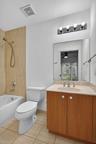 Tiled shower with handheld shower fixture, light wood-finish vanity, light-colored countertop, and a vanity mirror
