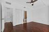 Room featuring wood-finish flooring, a ceiling fan, and tray ceiling