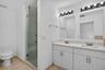 Dual vanity with rectangular undermount sinks, stone countertops, and overhead light fixtures