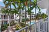 Balcony overlooking courtyard with palm trees, swimming pool, and multiple-story residential buildings