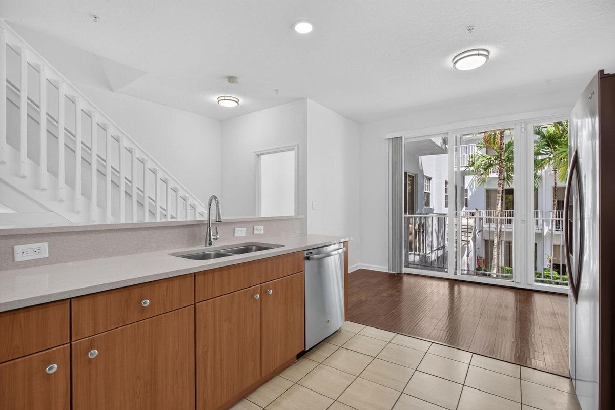 Kitchen featuring a double basin sink, light-toned countertops, and wood-finish cabinetry