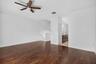 Wood-finish flooring throughout, white painted walls, and a ceiling fan with integrated lighting