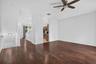 Wood-finish flooring throughout, high ceilings, and a ceiling fan with integrated lighting