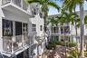 White stucco exterior with multiple balconies, sliding glass doors, and mature palm trees