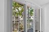 Sliding glass doors with vertical blinds open to a private balcony with a white metal railing