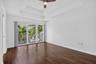 Dark wood-finish flooring with a tray ceiling and ceiling fan
